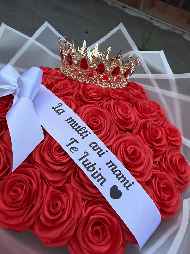 Close-up of red satin roses with a gold crown and a ribbon reading La mulți ani mami